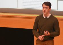 Student stands in front of projector screen giving a presentation